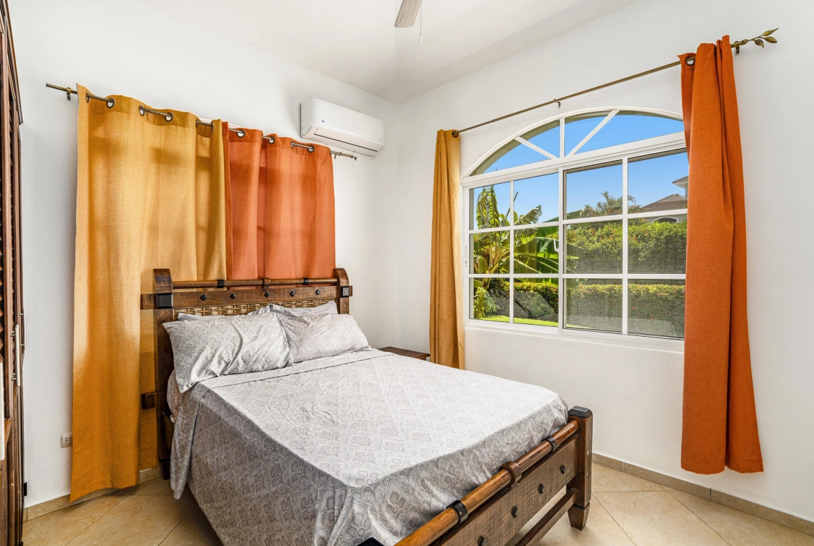 buyDRproperty Spacious bedroom with oversized bed, patterned bedding, and orange curtains. Sosua Real Estate