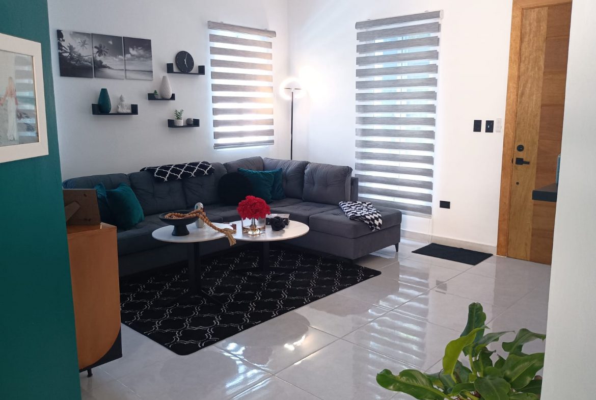 buyDRproperty Modern living room with gray sofa, black rug, and white walls. Sosua Real Estate