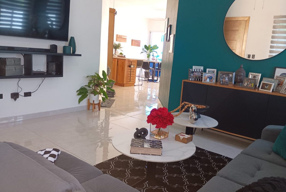 buyDRproperty Modern living room with teal accent wall and round mirror, part of a Puerto Plata villa. Sosua Real Estate