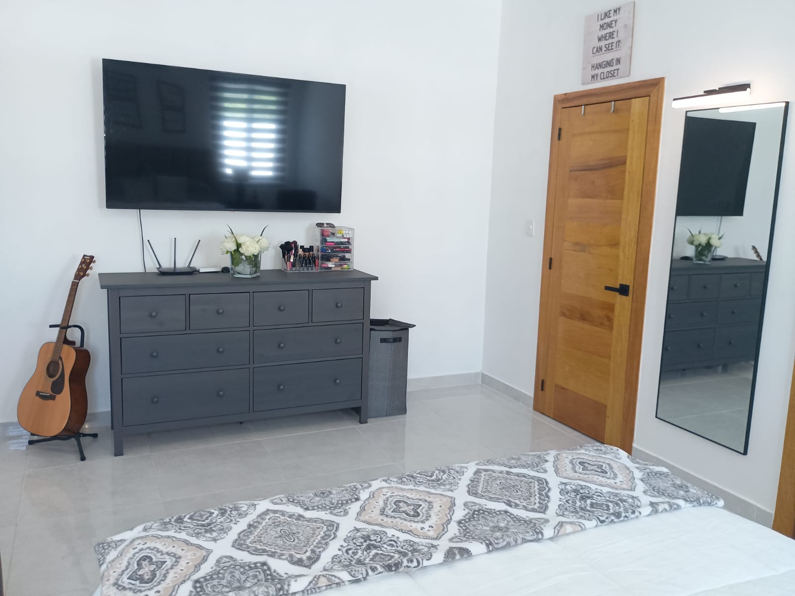 buyDRproperty Modern bedroom with gray dresser, TV, and guitar in a Puerto Plata villa. Sosua Real Estate