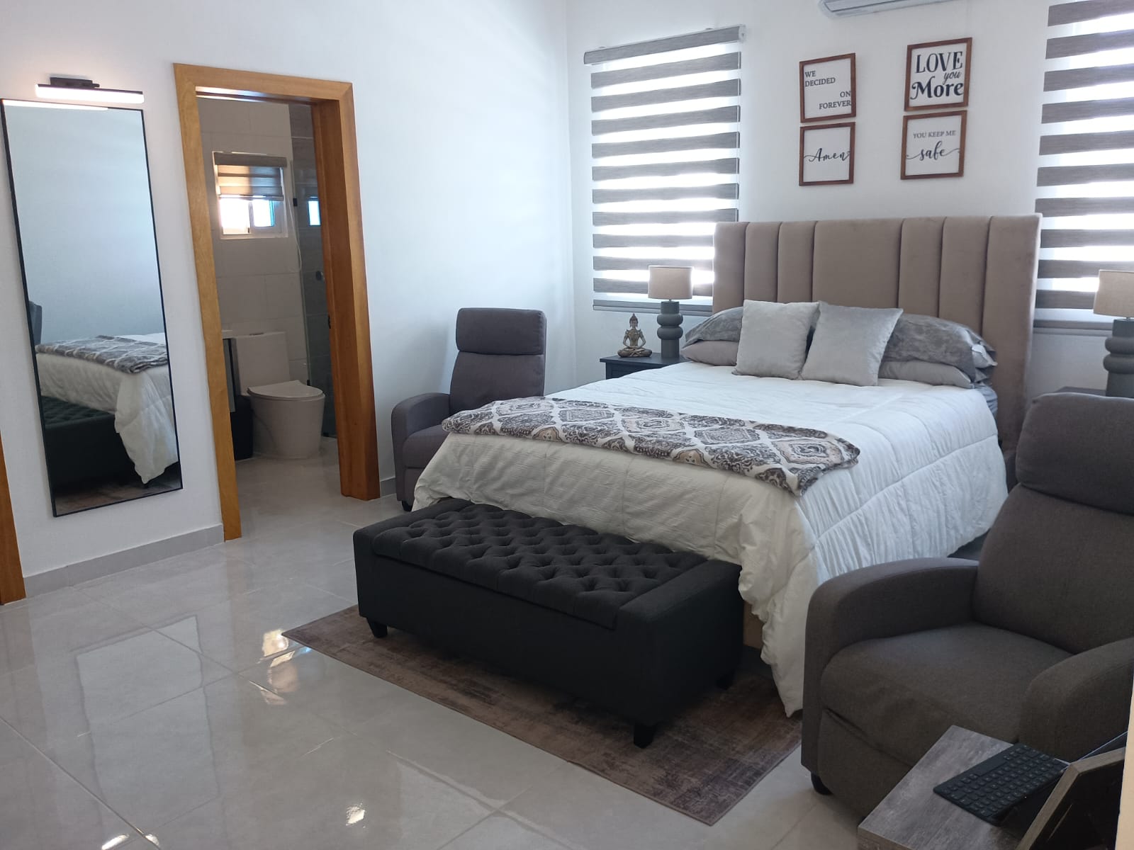 buyDRproperty Modern bedroom with neutral tones, bed, and two armchairs. Sosua Real Estate