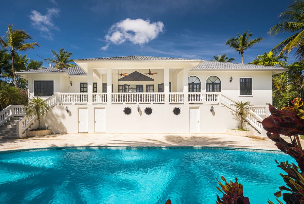 buyDRproperty Luxury Caribbean villa with pool and palm trees under a blue sky. Sosua Real Estate