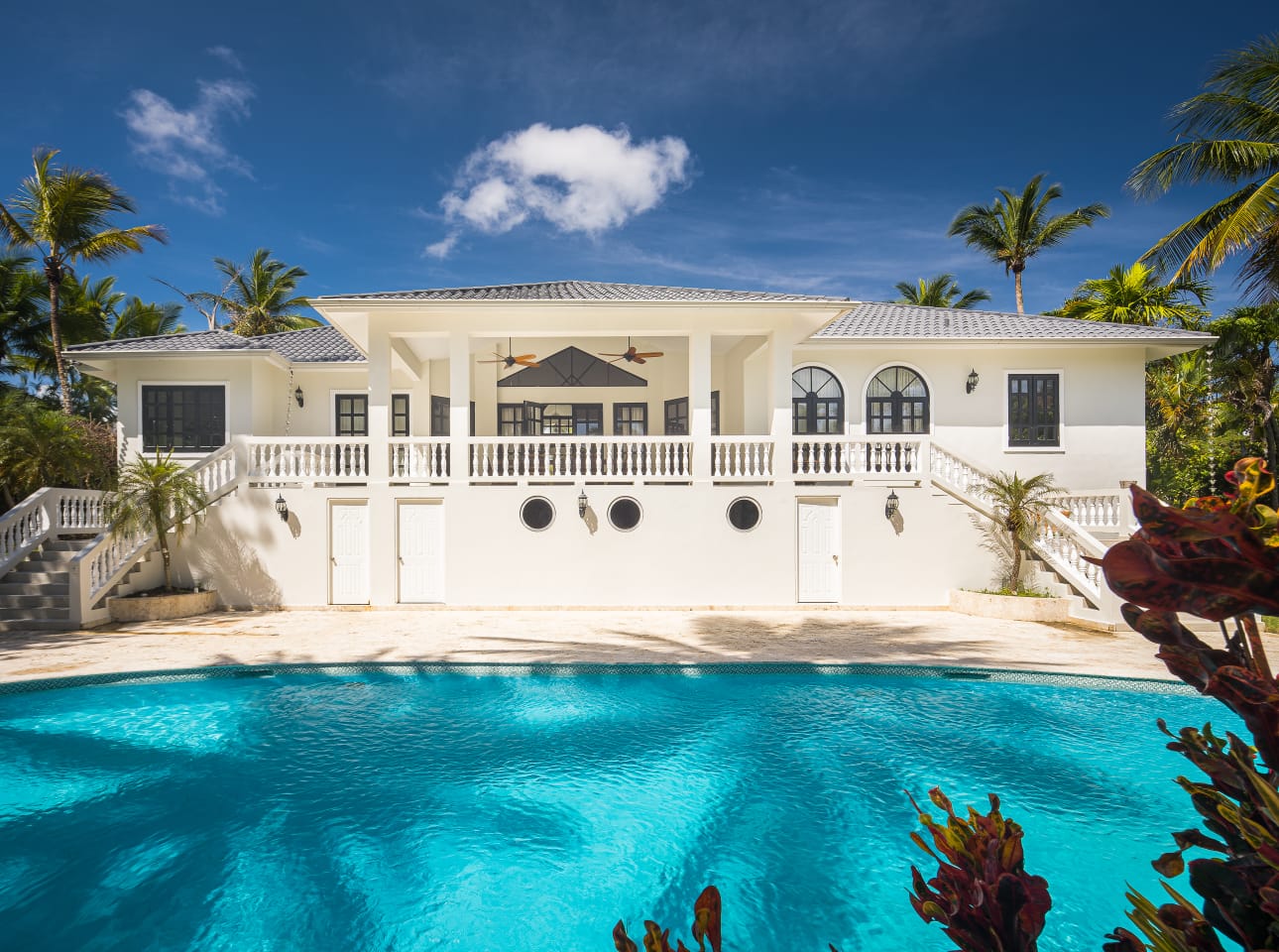buyDRproperty Luxury Caribbean villa with pool and palm trees under a blue sky. Sosua Real Estate
