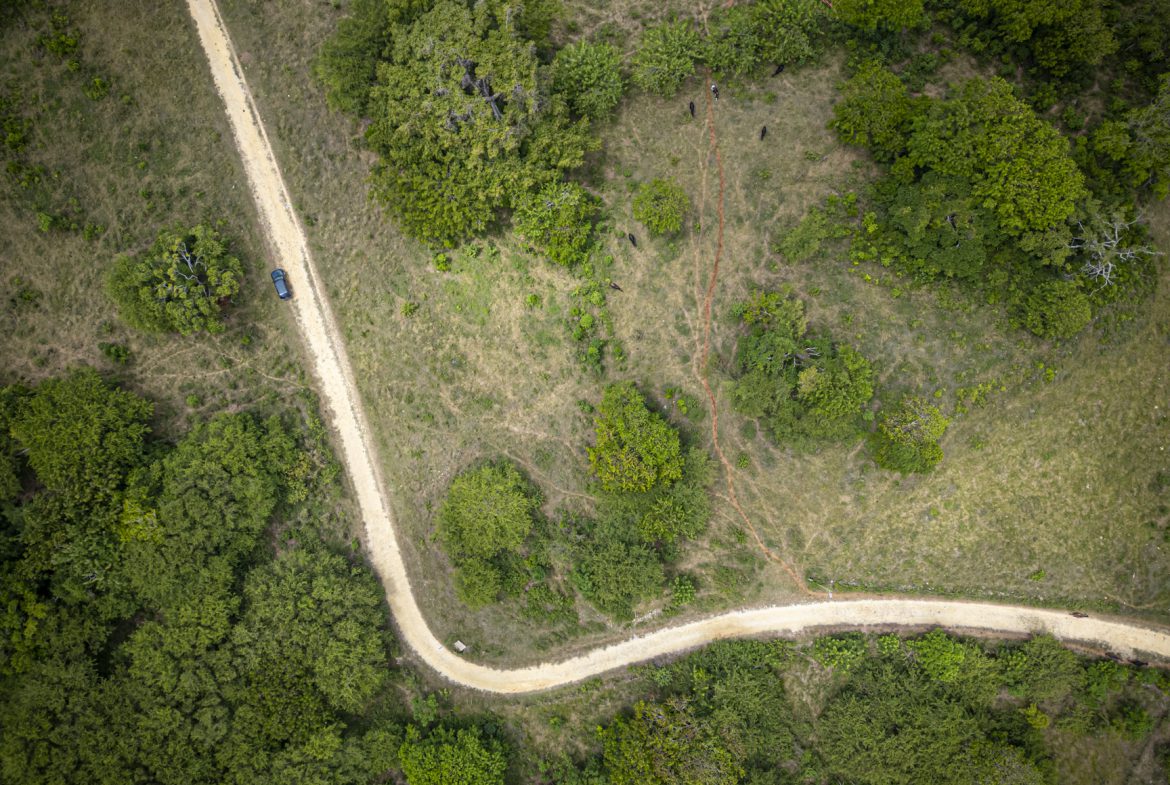 buyDRproperty Aerial view of a winding dirt road through a rural landscape, with a vehicle parked on the side. Sosua Real Estate