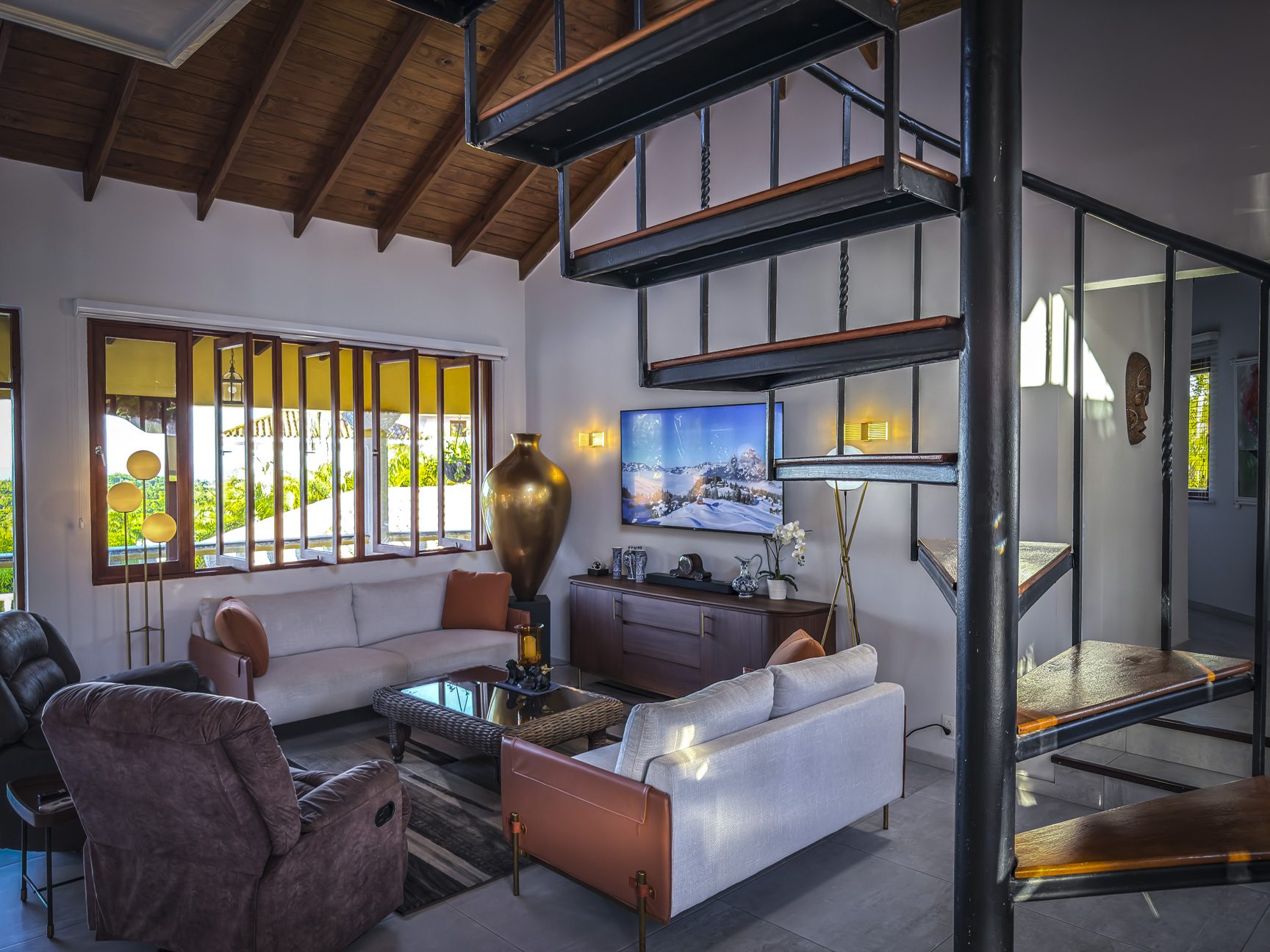 buyDRproperty Living room in a luxury villa for sale with ocean views, featuring a spiral staircase and modern decor. Sosua Real Estate
