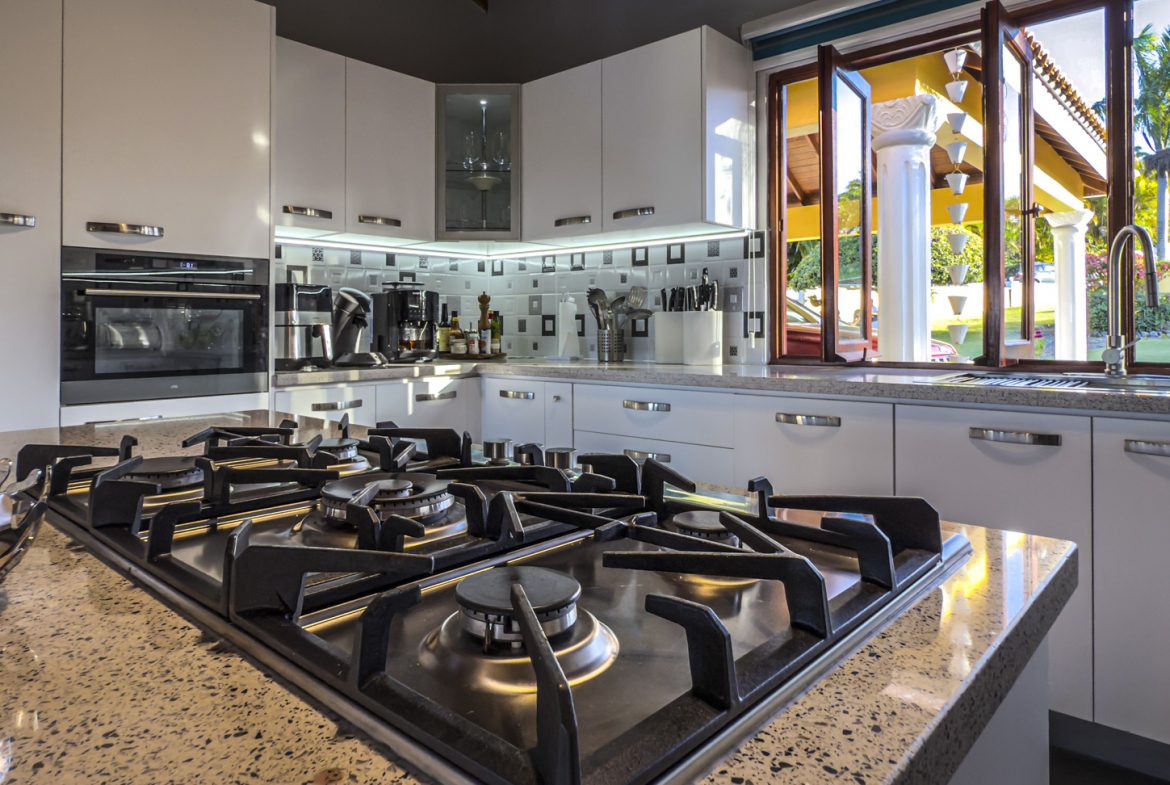 buyDRproperty Modern kitchen in a luxury villa with ocean views, featuring a gas cooktop and white cabinets. Sosua Real Estate