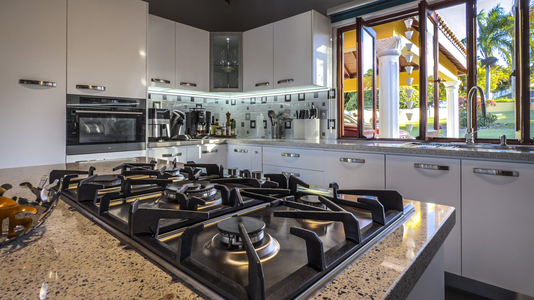 buyDRproperty Modern kitchen in a luxury villa with ocean views, featuring a gas cooktop and white cabinets. Sosua Real Estate