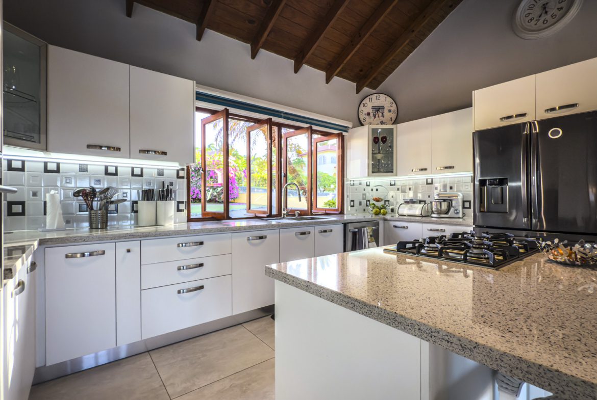 buyDRproperty Modern white kitchen in a luxury villa with ocean views, featuring granite countertops and stainless steel appliances. Sosua Real Estate