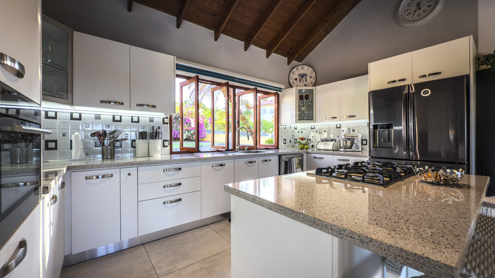 buyDRproperty Modern white kitchen in a luxury villa with ocean views, featuring granite countertops and stainless steel appliances. Sosua Real Estate