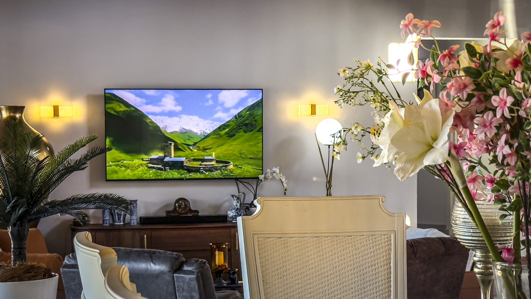 buyDRproperty Living room with TV showing a mountain landscape, decorative plants, and stylish furniture. Sosua Real Estate