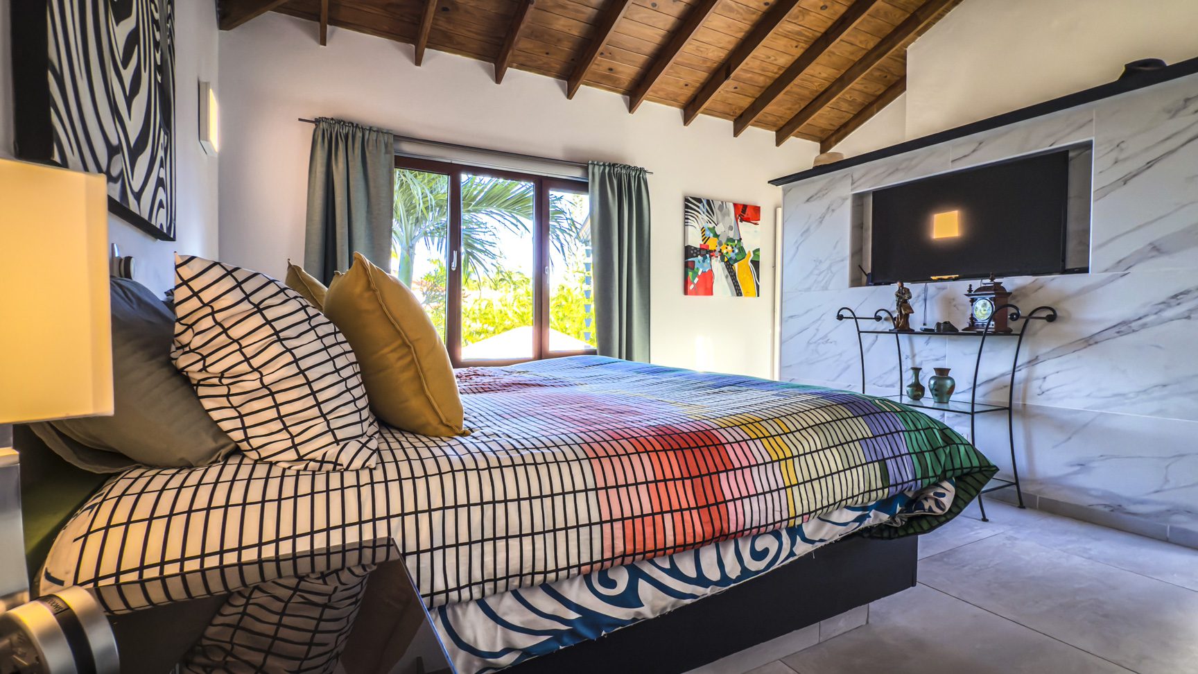 buyDRproperty Bedroom interior with ocean view villa for sale, featuring colorful bedspread, artwork, and built-in TV. Sosua Real Estate