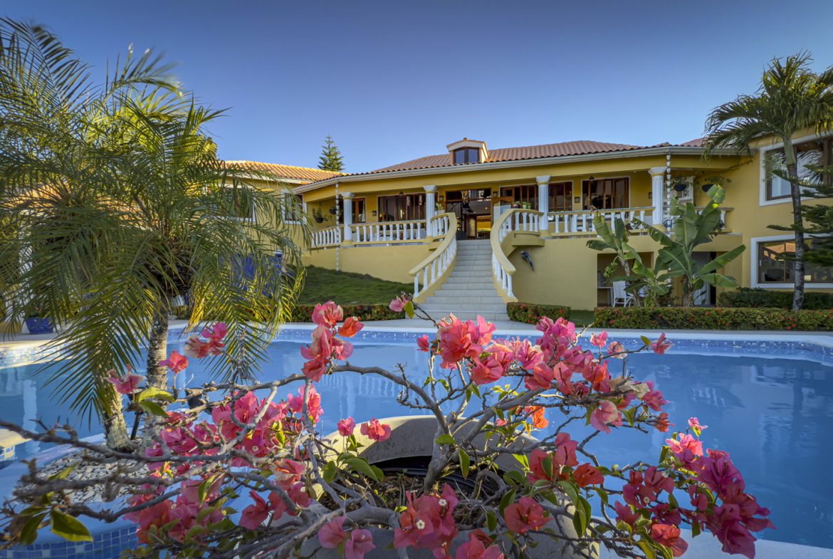buyDRproperty Luxury villa with a pool and bougainvillea. Ocean views and a lush garden create a tropical paradise. Sosua Real Estate
