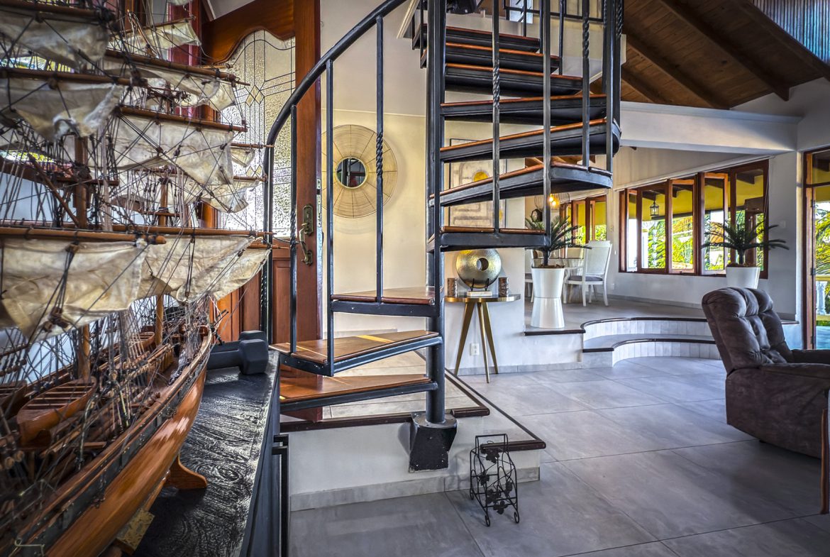 buyDRproperty Interior of a luxury villa with a spiral staircase and model ship, showcasing ocean views. Sosua Real Estate