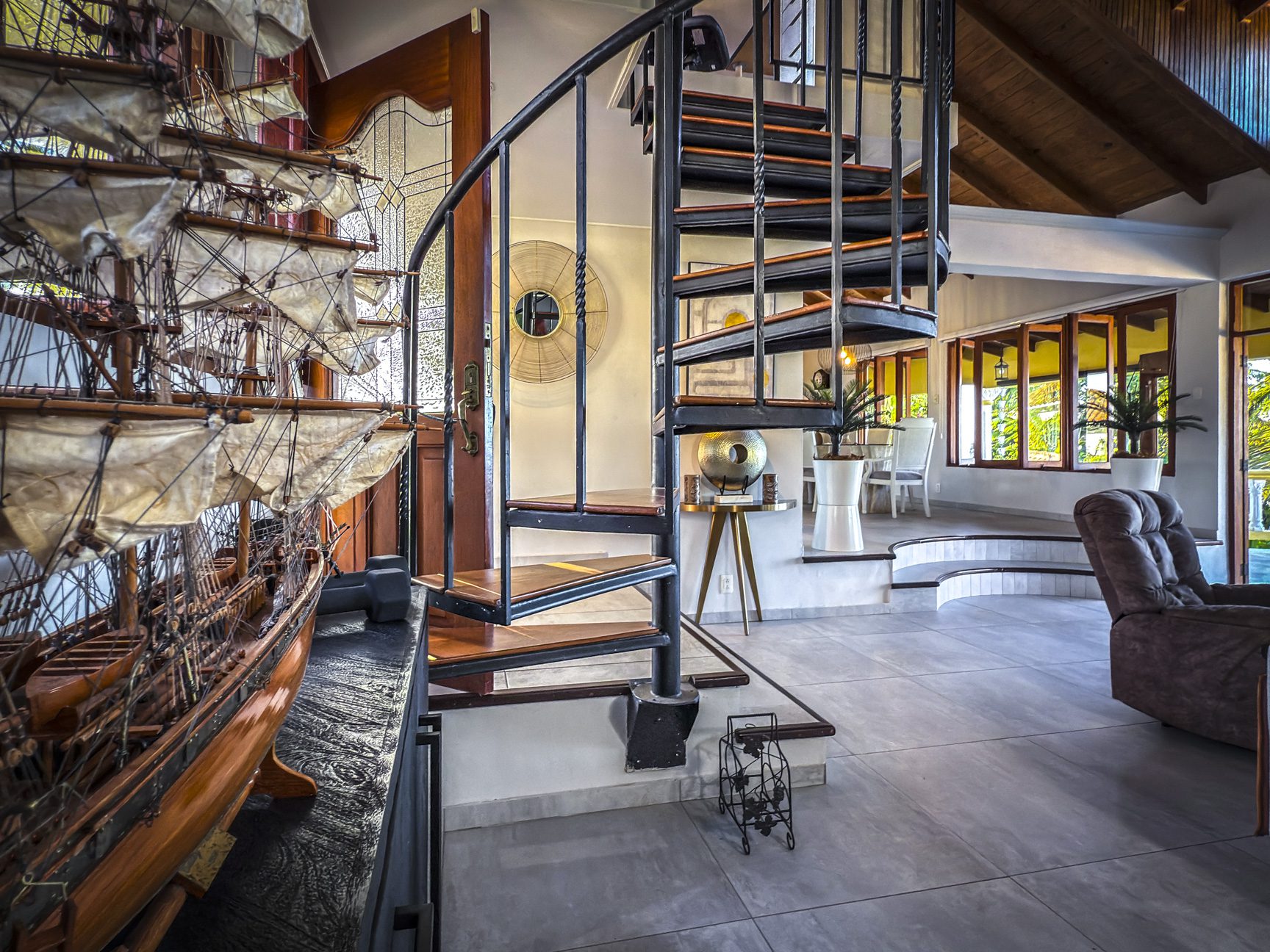 buyDRproperty Interior of a luxury villa with a spiral staircase and model ship, showcasing ocean views. Sosua Real Estate
