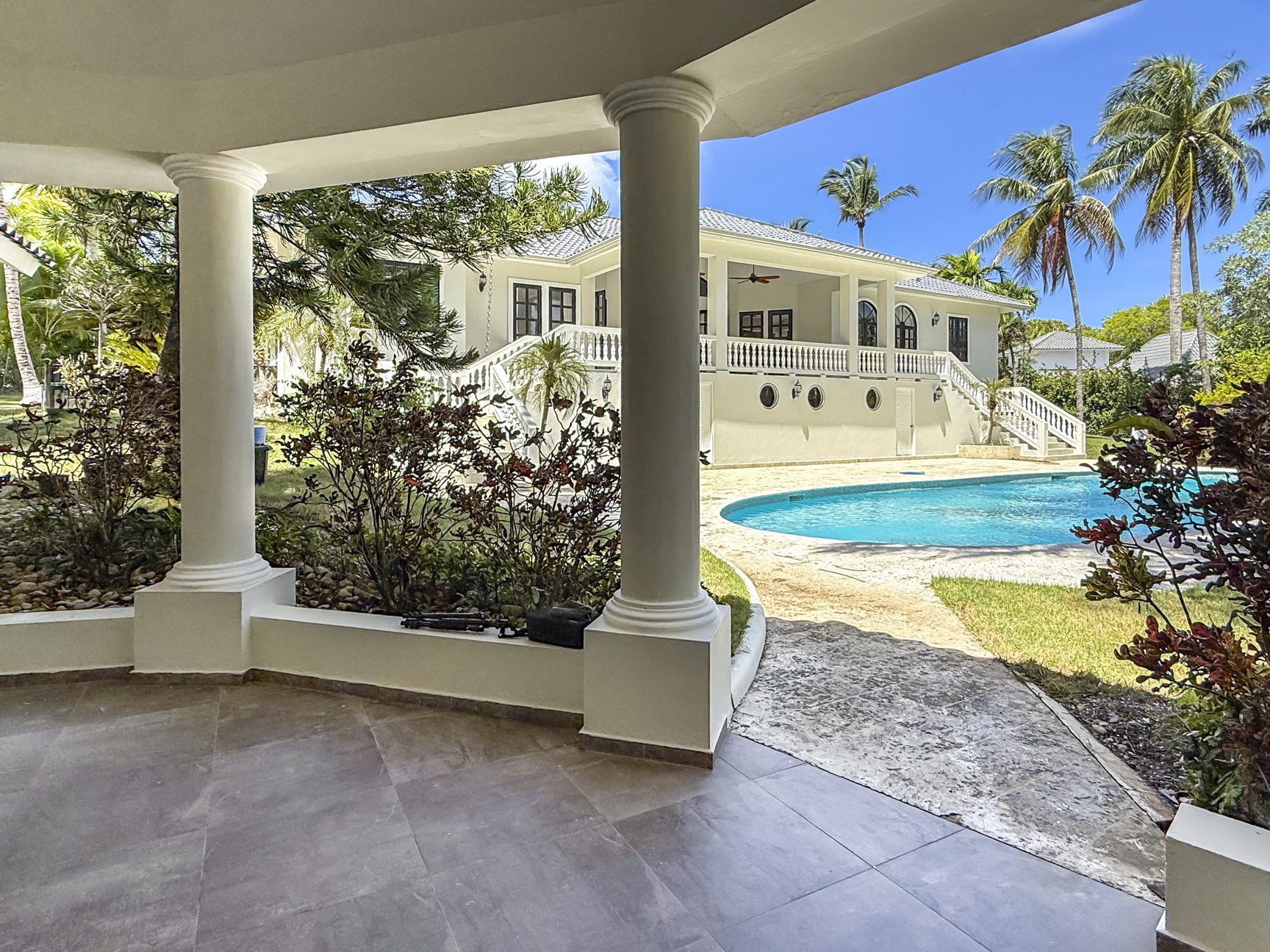 buyDRproperty Luxury villa with pool in the Caribbean. Vacation rental overlooking a turquoise pool and palm trees. Sosua Real Estate