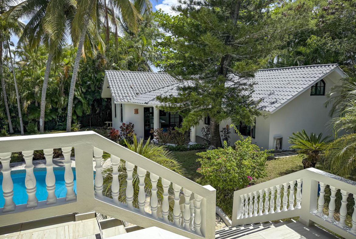 buyDRproperty White beach house with pool, palm trees, and lush tropical foliage. Sosua Real Estate
