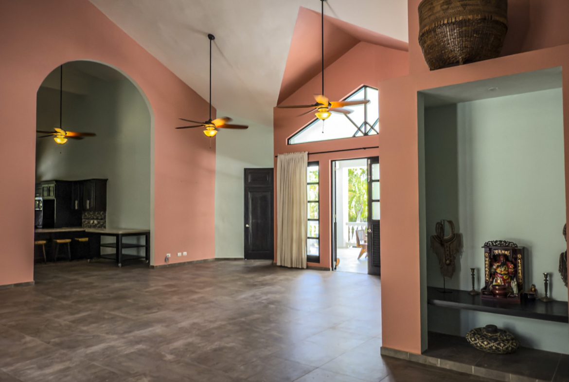 buyDRproperty Spacious open concept living room with high ceilings, coral walls, and ceiling fans. Sosua Real Estate
