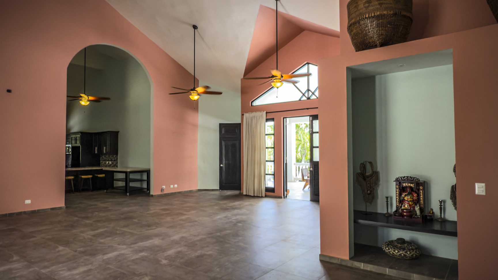 buyDRproperty Spacious open concept living room with high ceilings, coral walls, and ceiling fans. Sosua Real Estate