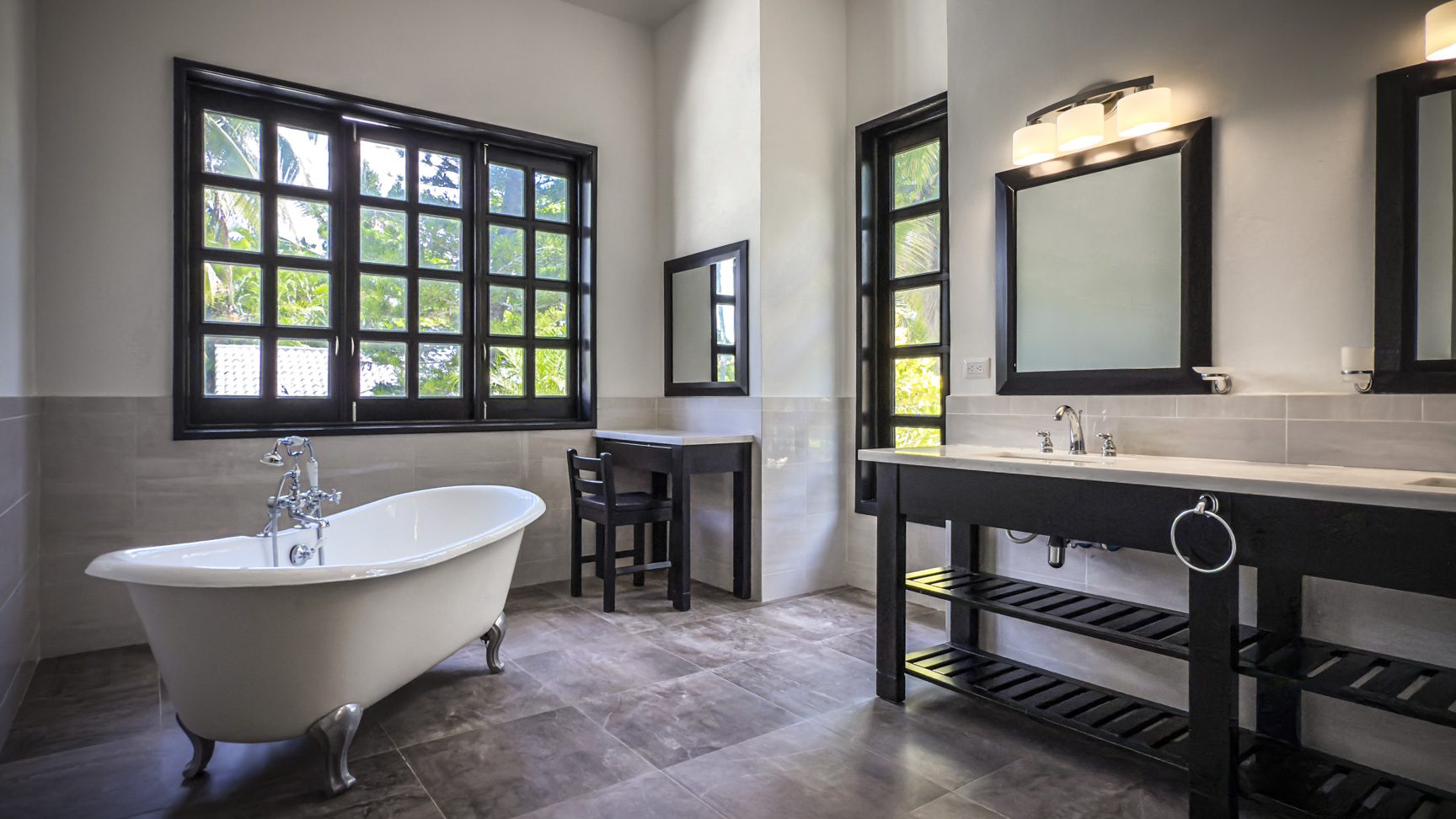 buyDRproperty Modern bathroom design with clawfoot tub, black vanity, and large window. Sosua Real Estate