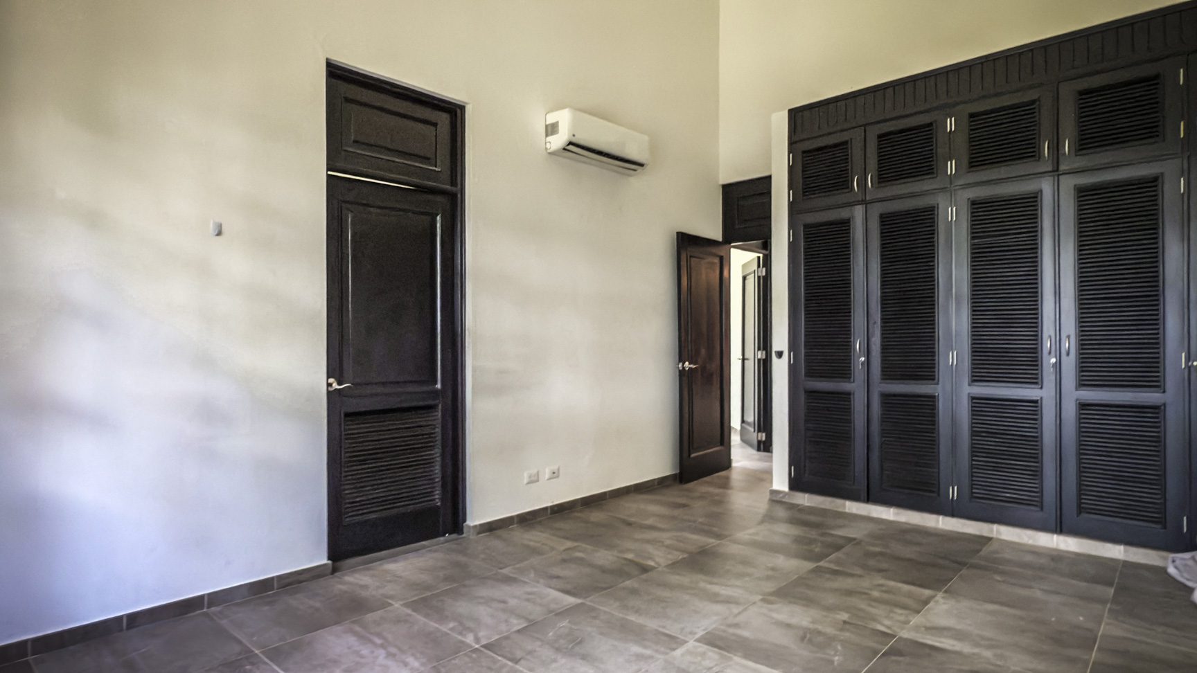 buyDRproperty Modern bedroom with dark wood closet and door, interior design Sosua Real Estate