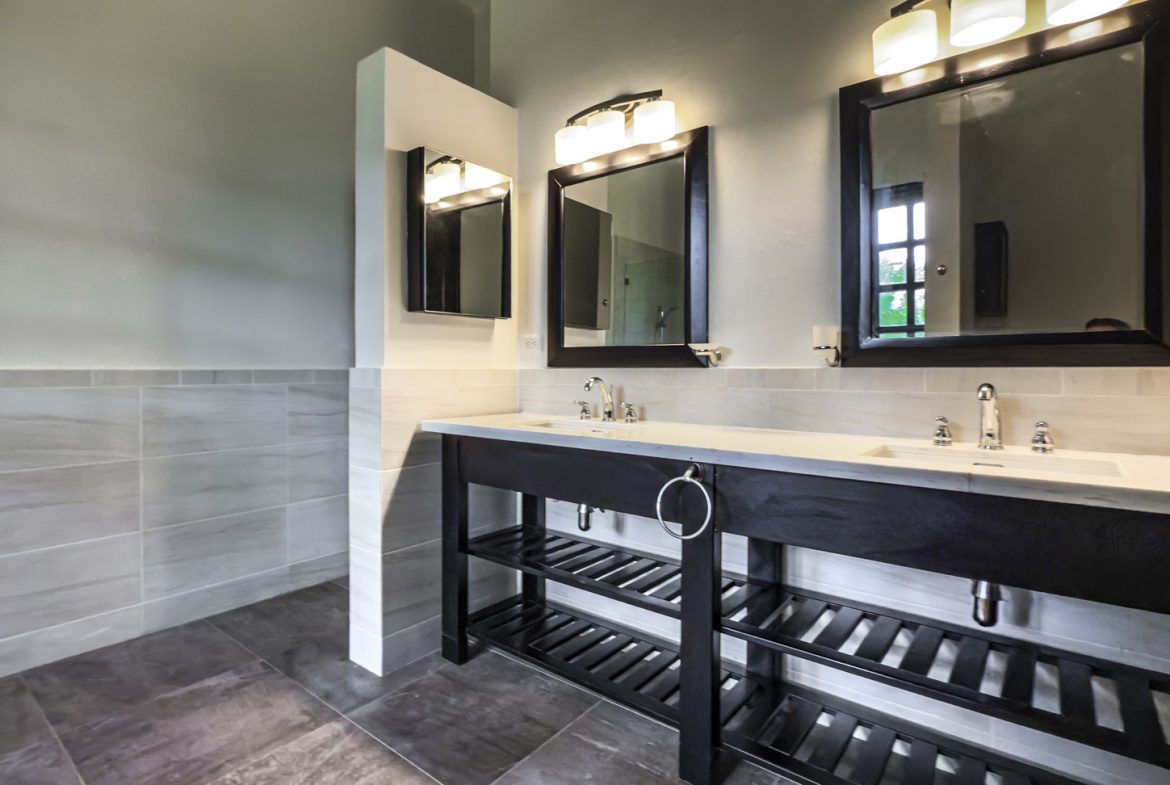 buyDRproperty Modern bathroom with double sink vanity, black frame mirrors, and gray tile. Sosua Real Estate