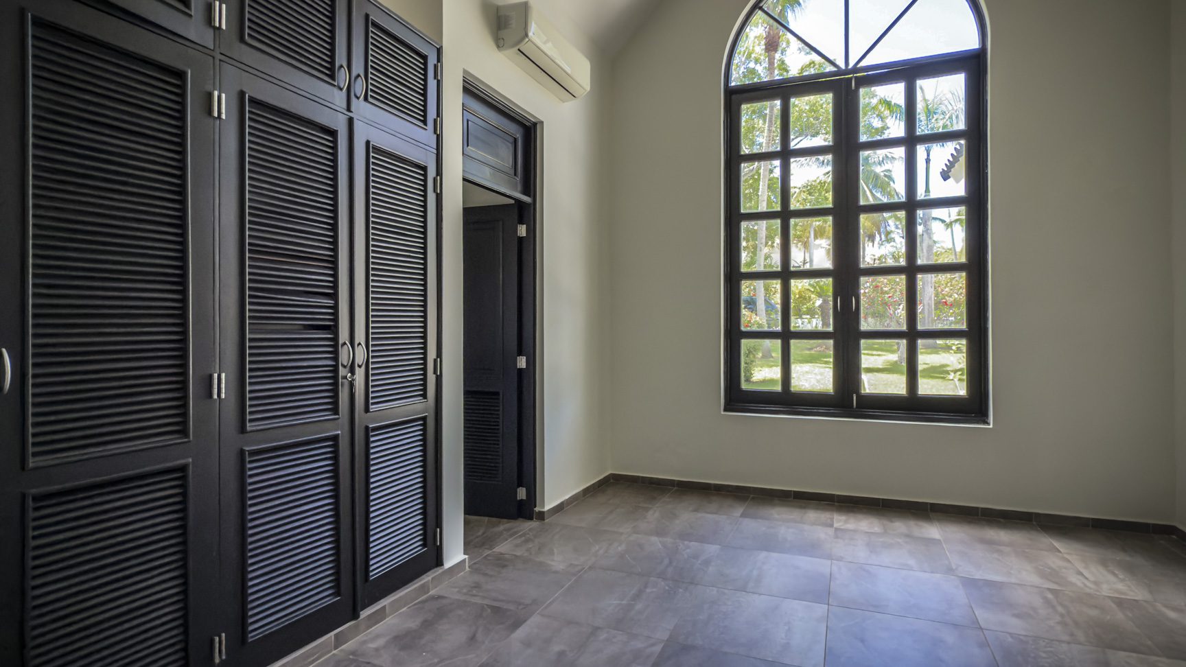 buyDRproperty Luxury home interior with black wardrobe and arched window, modern design. Sosua Real Estate