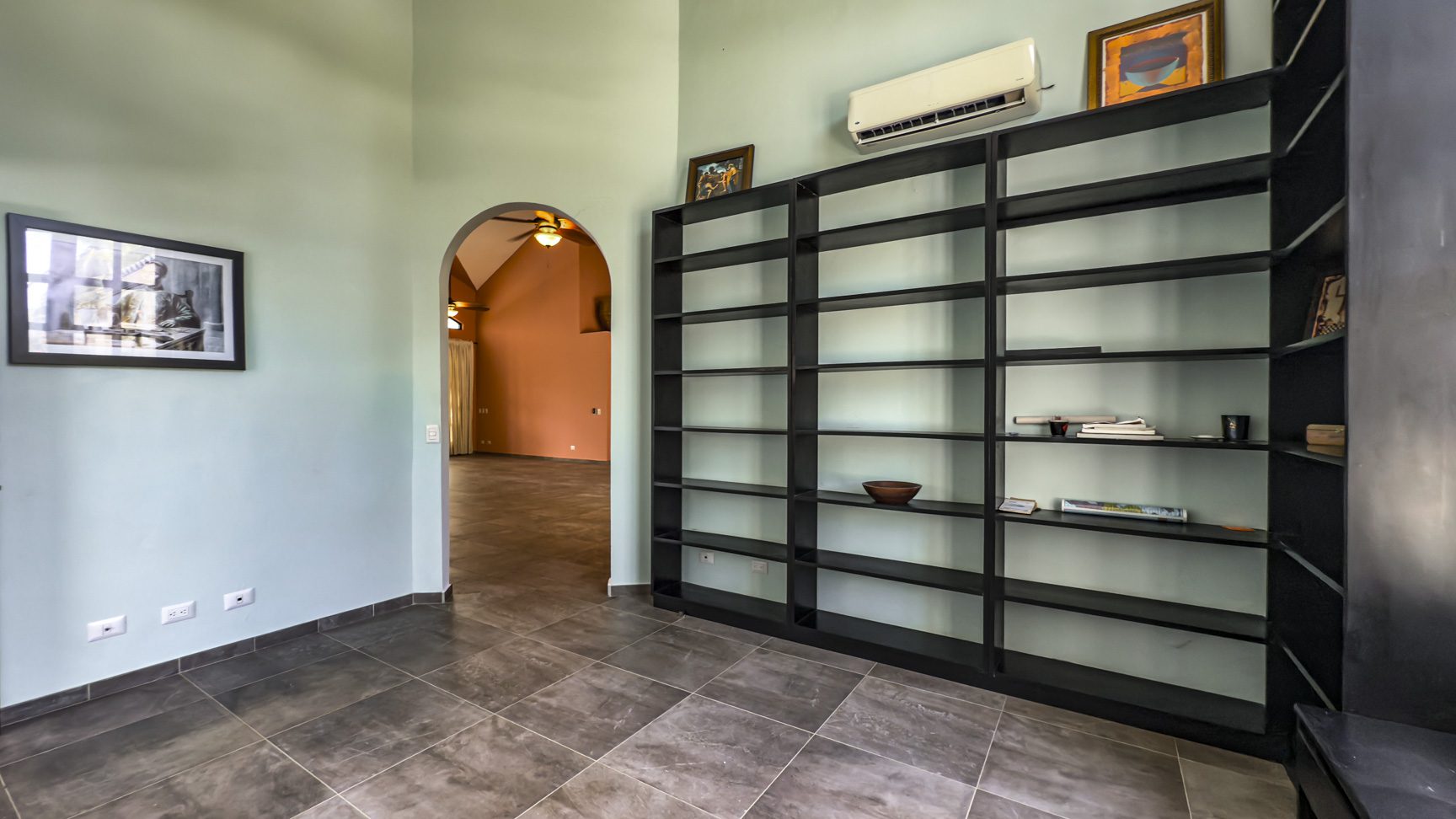 buyDRproperty Modern living room with black bookshelf, artwork, and archway to another room. Sosua Real Estate