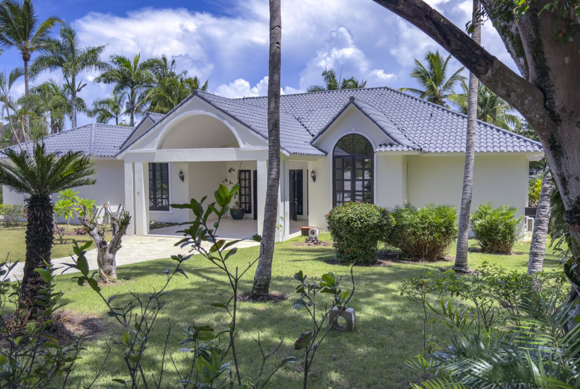 buyDRproperty Luxury tropical villa with gray tile roof and lush landscaping, perfect for Caribbean vacation rentals. Sosua Real Estate