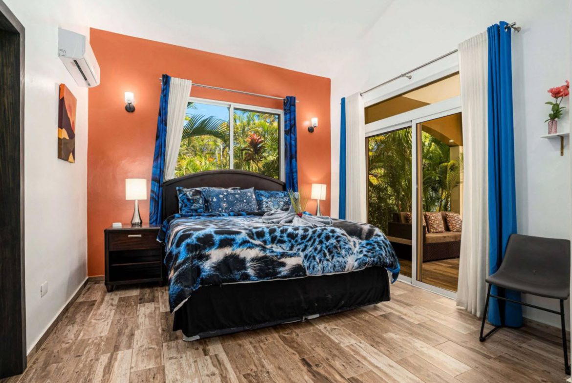 buyDRproperty Elegant bedroom in Villa Lotus with blue and white bed linens, and view of lush greenery. Sosua Real Estate