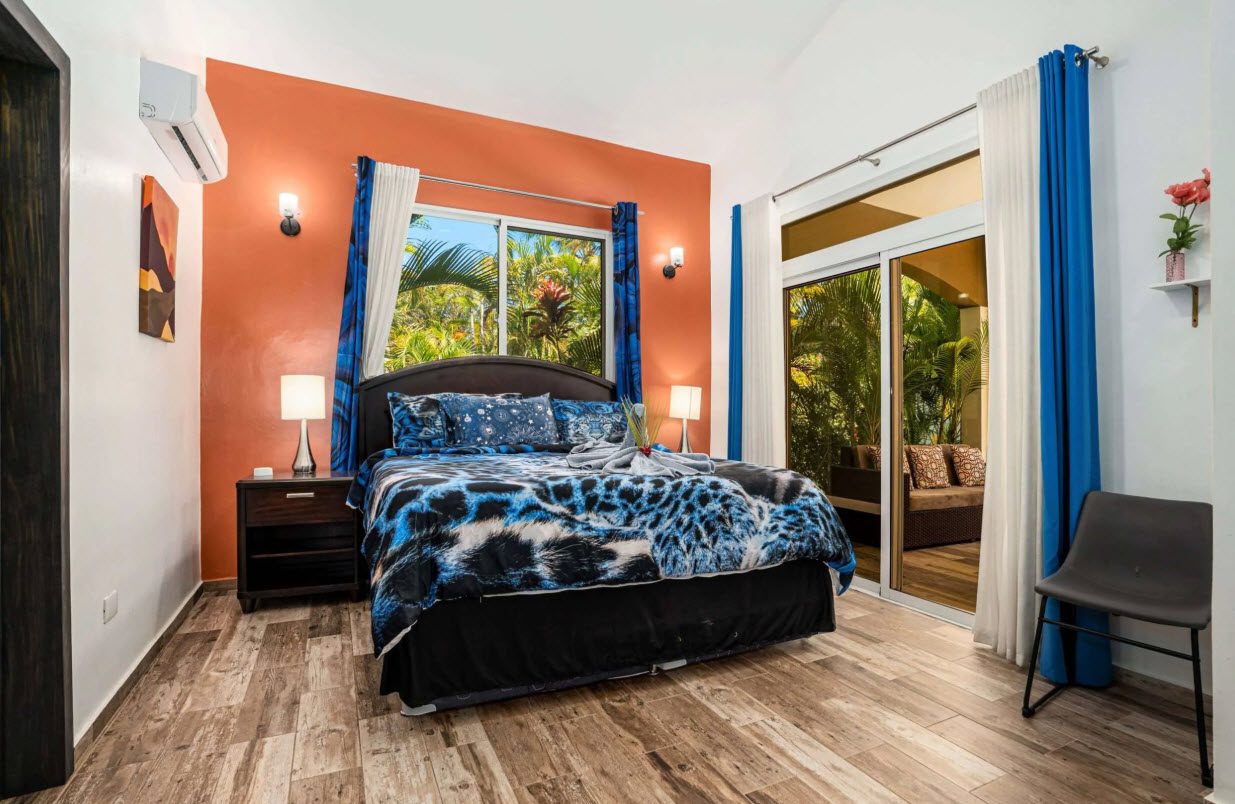 buyDRproperty Elegant bedroom in Villa Lotus with blue and white bed linens, and view of lush greenery. Sosua Real Estate