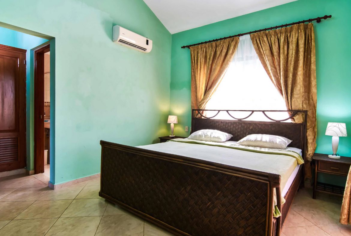 buyDRproperty Bedroom with a large bed, curtains, and an air conditioner in a Residential Hispaniola villa. Sosua Real Estate