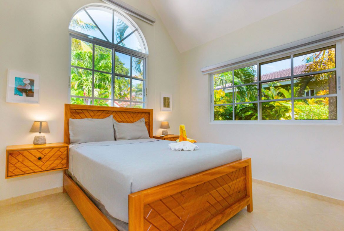buyDRproperty Bedroom in a 3 BR Villa in Sosúa with large windows and wooden bed frame. Sosua Real Estate