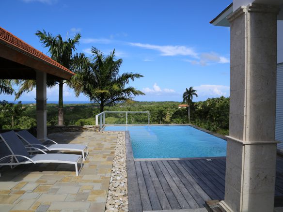 buyDRproperty Infinity pool with lounge chairs overlooking tropical landscape Sosua Real Estate
