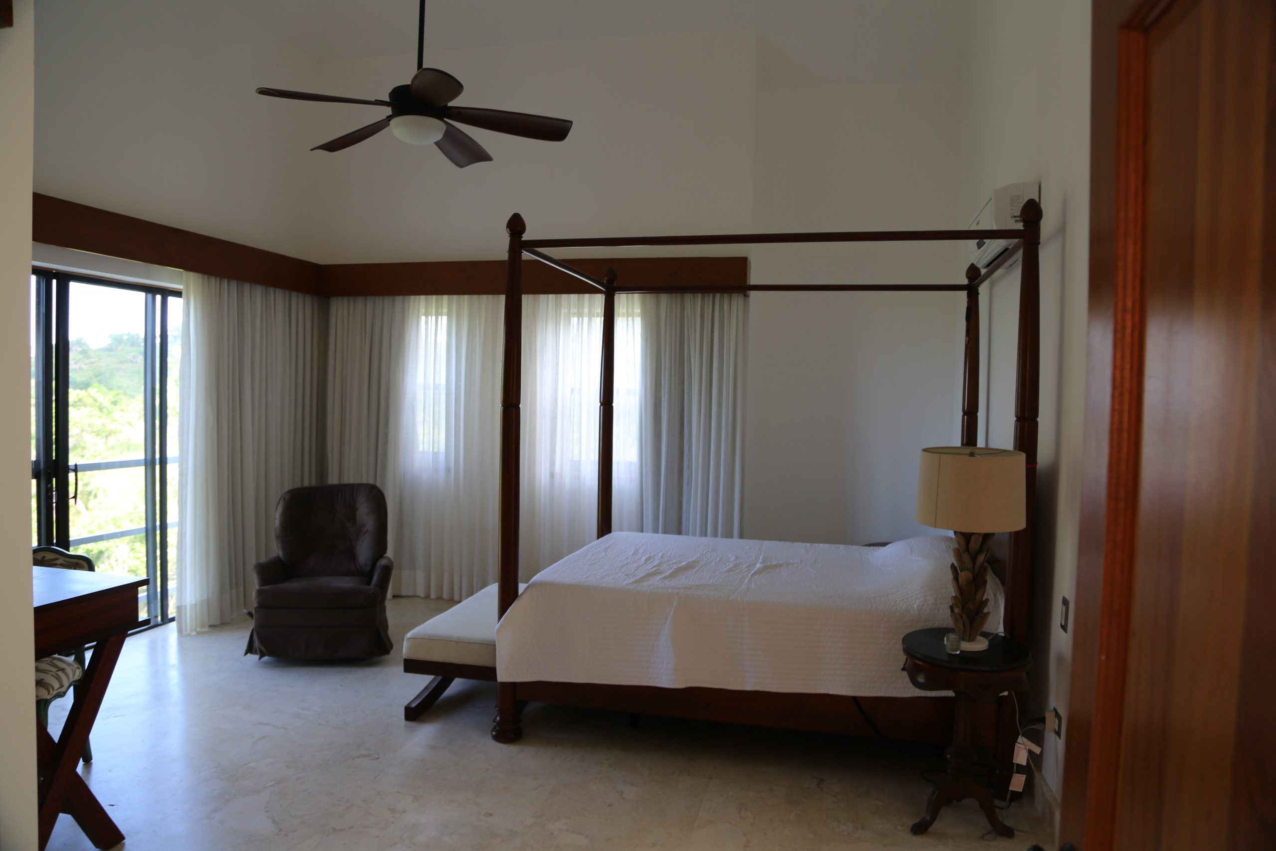 buyDRproperty Luxurious bedroom with a four-poster bed, side table, and armchair. Sosua Real Estate