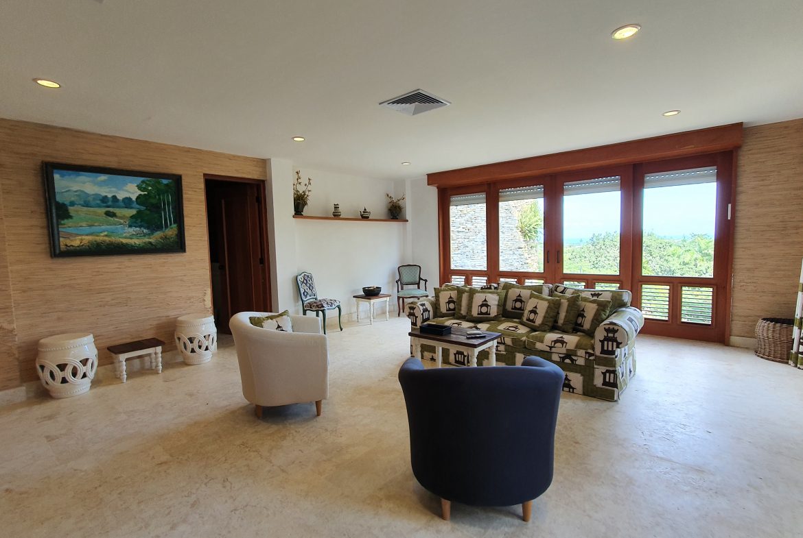 buyDRproperty Elegant living room with modern furniture, large windows, and landscape painting. Sosua Real Estate