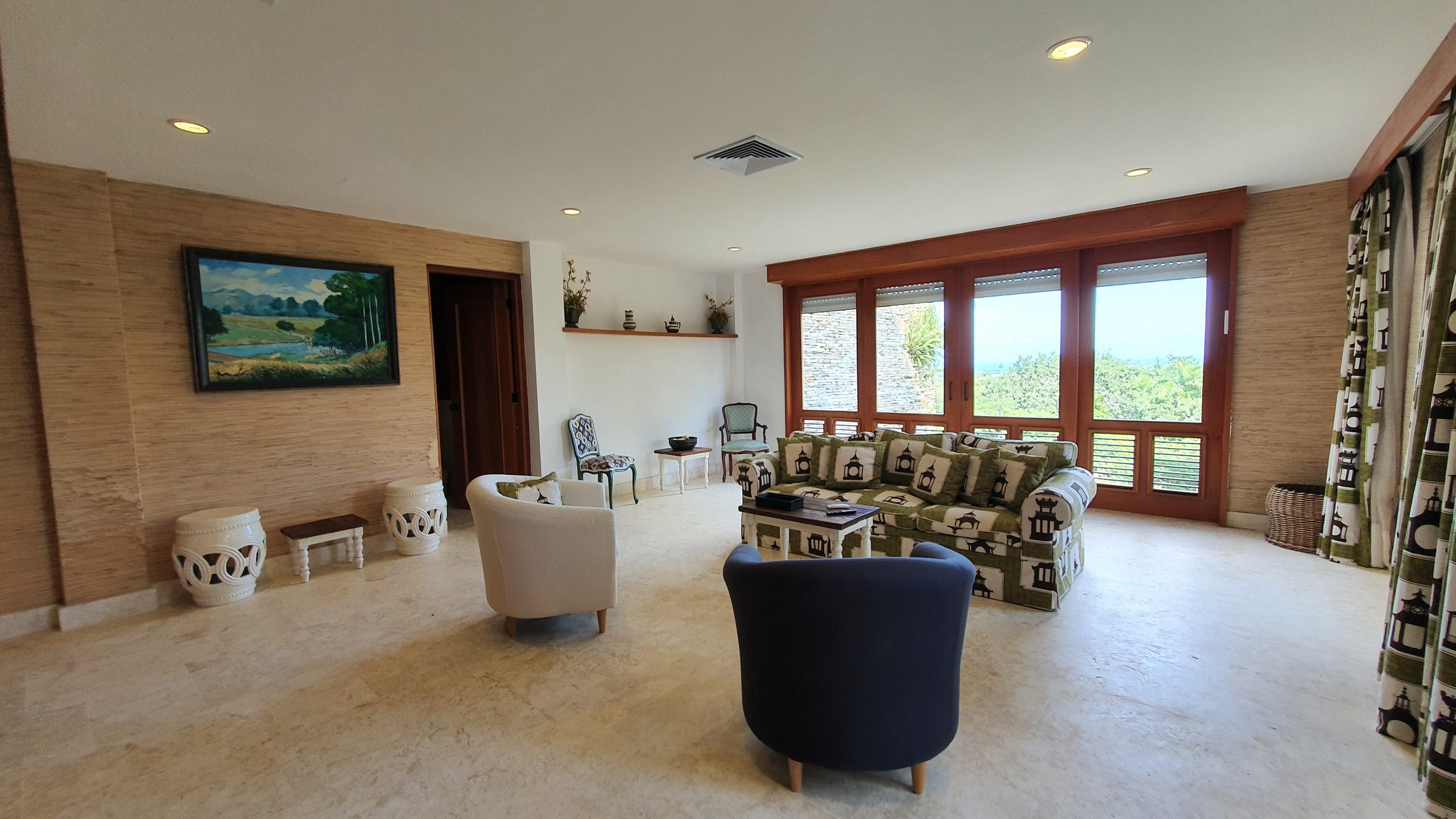 buyDRproperty Elegant living room with modern furniture, large windows, and landscape painting. Sosua Real Estate