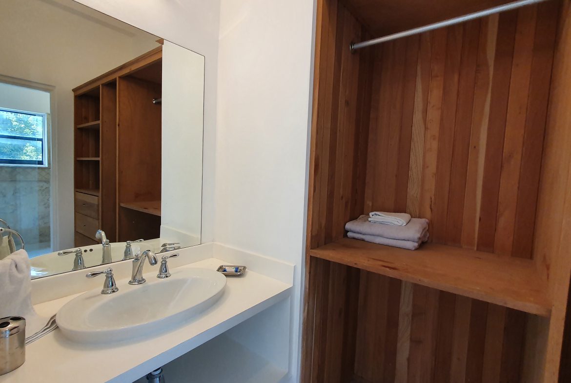 buyDRproperty Bathroom vanity with oval sink, large mirror, and built-in wooden closet Sosua Real Estate