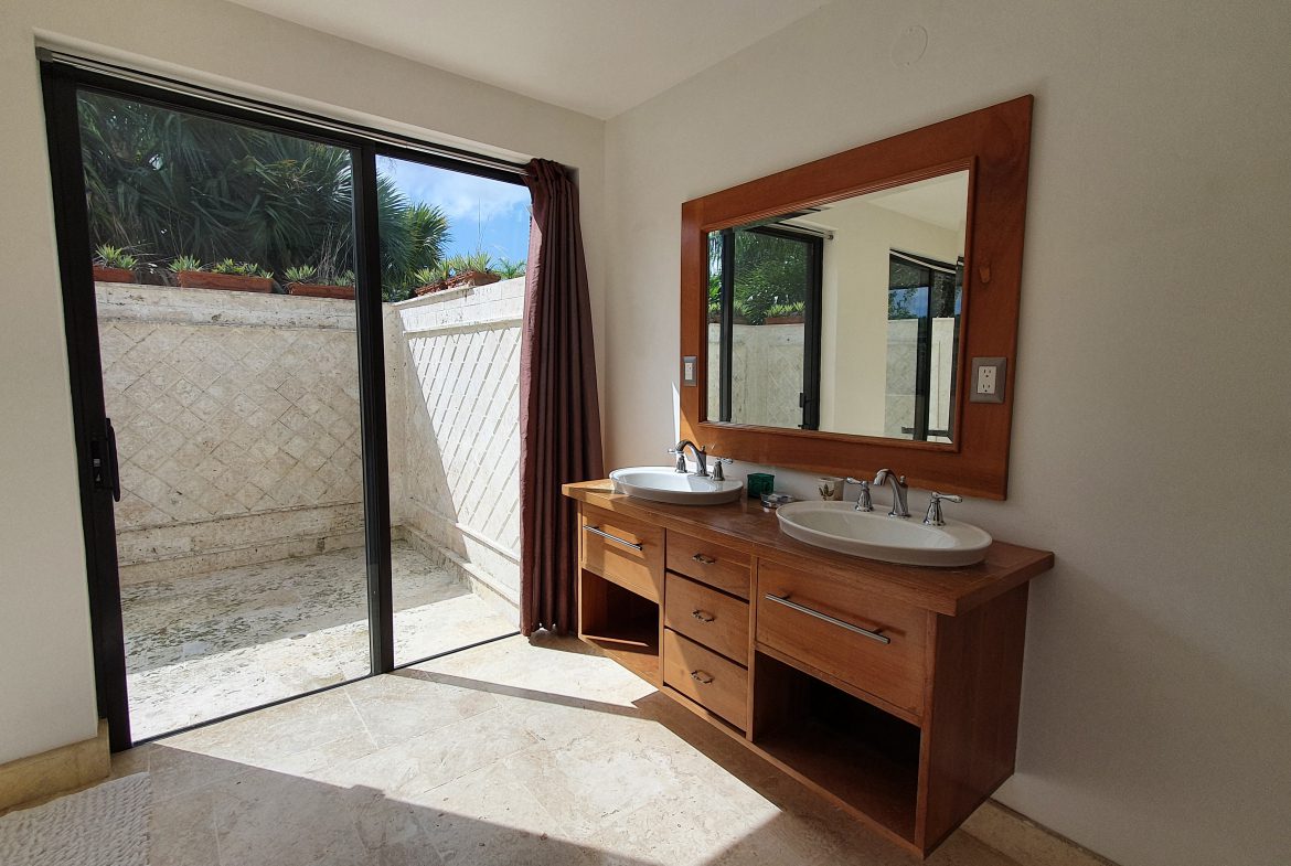 buyDRproperty Modern bathroom with double vanity, wood cabinet, and sliding door to outdoor space. Sosua Real Estate