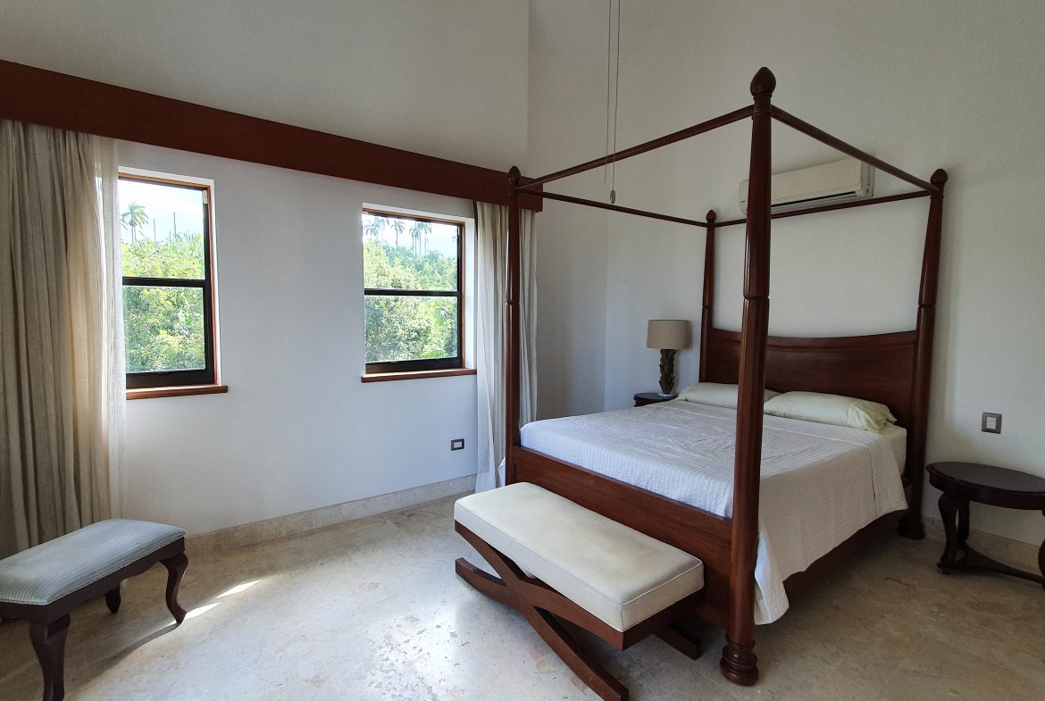 buyDRproperty Luxury bedroom with a dark wood four-poster bed, bench, and side table. Bedroom design. Sosua Real Estate