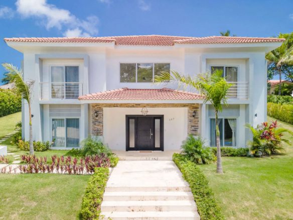buyDRproperty Luxury two-story villa with a red tile roof and manicured lawn. Sosua Real Estate