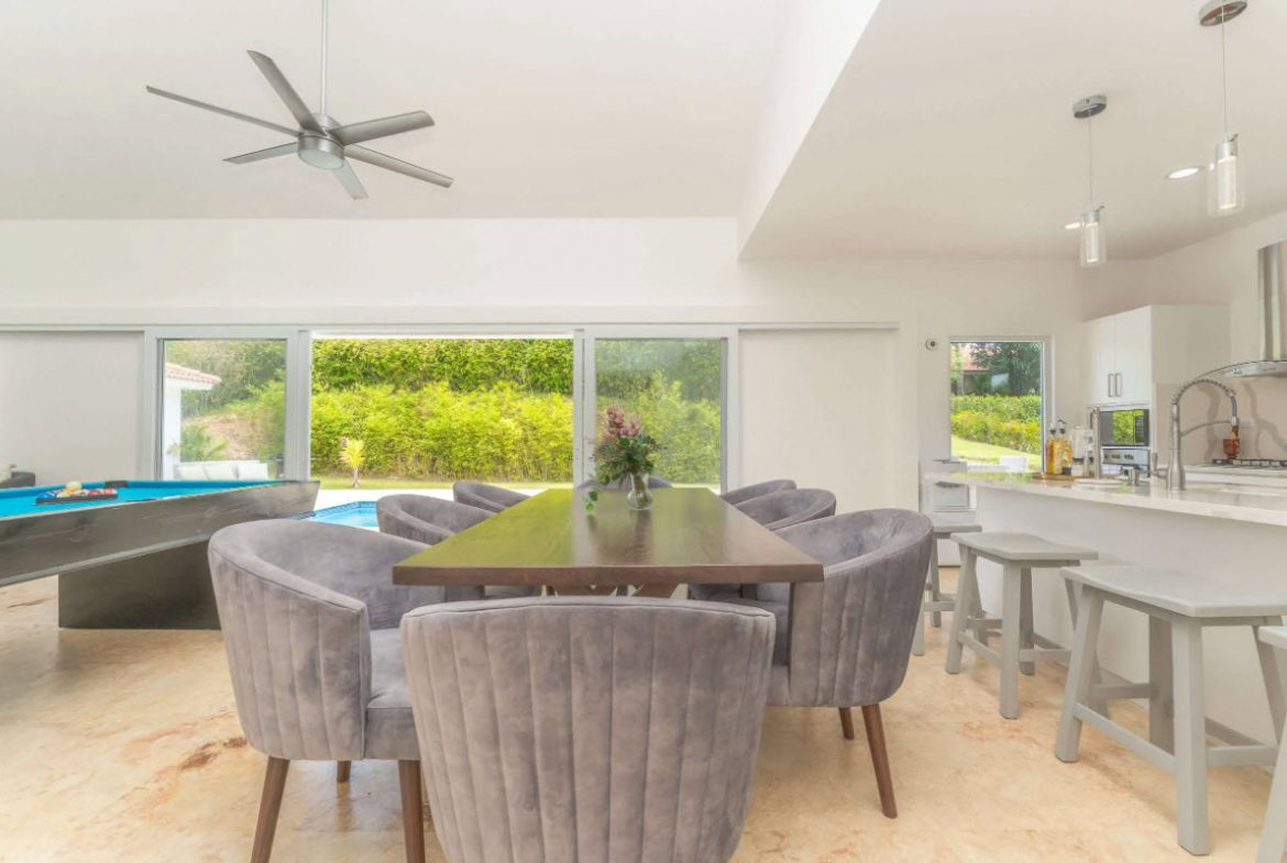 buyDRproperty Open-concept living space with dining table, pool table, and outdoor pool view. Sosua Real Estate