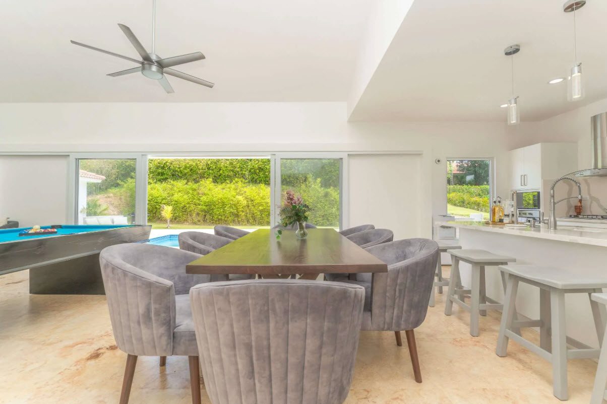buyDRproperty Open-concept living space with dining table, pool table, and outdoor pool view. Sosua Real Estate
