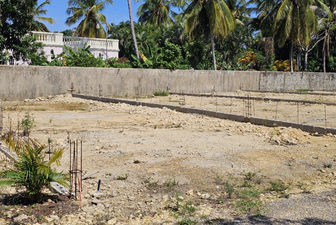 buyDRproperty Construction site with foundation and rebar, tropical trees in background. Sosua Real Estate