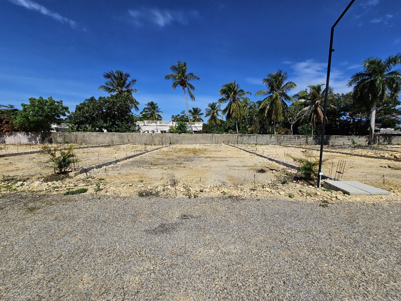 buyDRproperty Cleared land ready for construction in a tropical setting with palm trees and blue sky. Sosua Real Estate