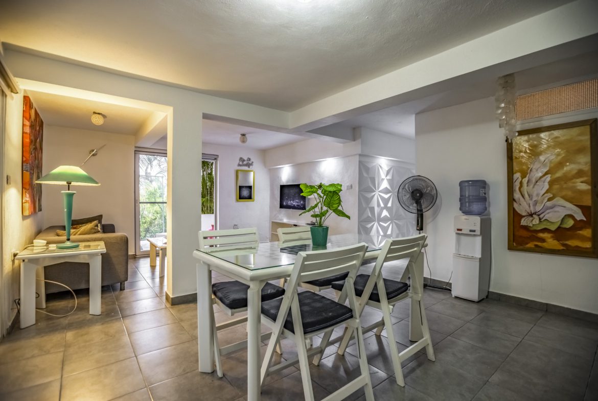 buyDRproperty Modern dining area with glass table, white chairs, and vibrant artwork Sosua Real Estate