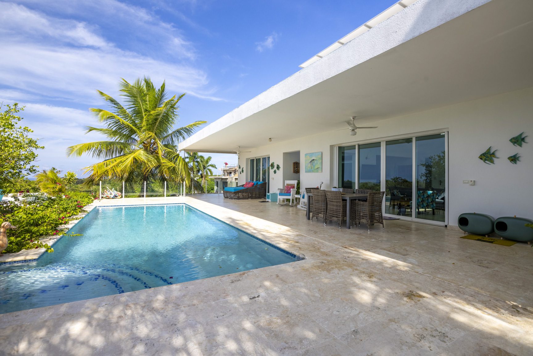 buyDRproperty Luxury villa pool with patio and palm tree under blue sky Sosua Real Estate