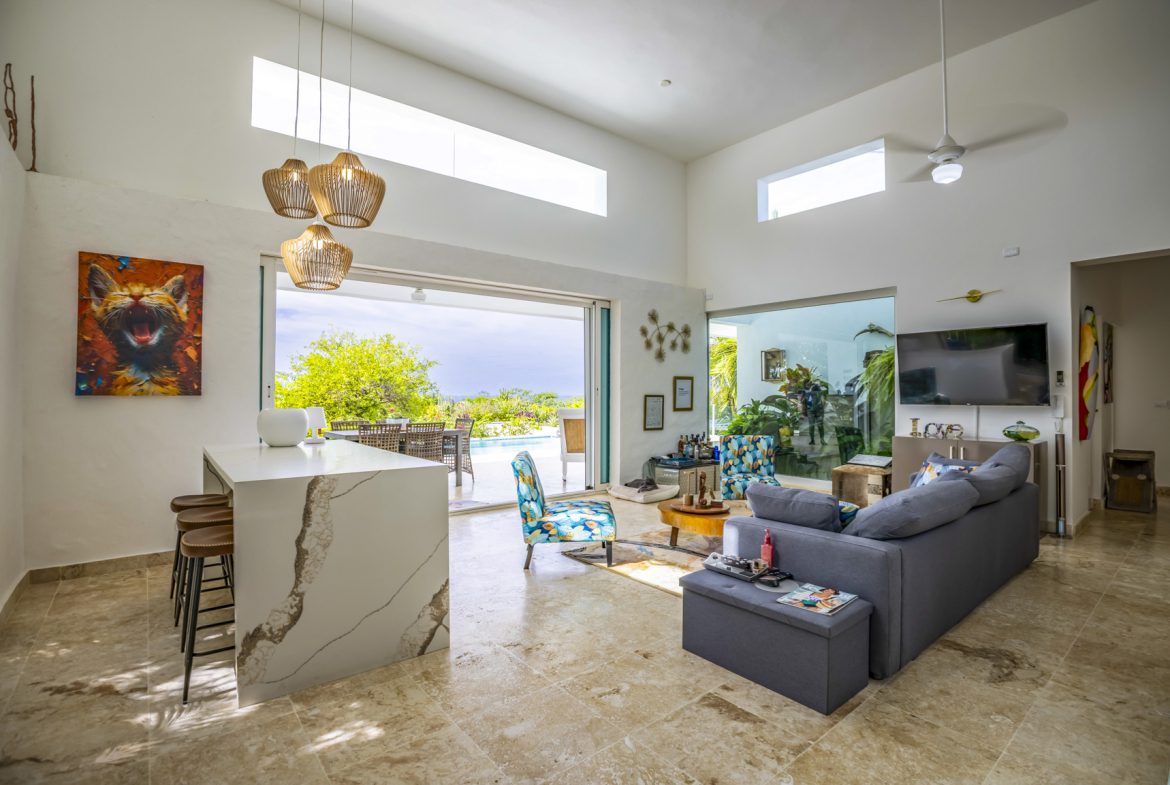 buyDRproperty Bright, modern living room with pool view through open sliding doors. Sosua Real Estate