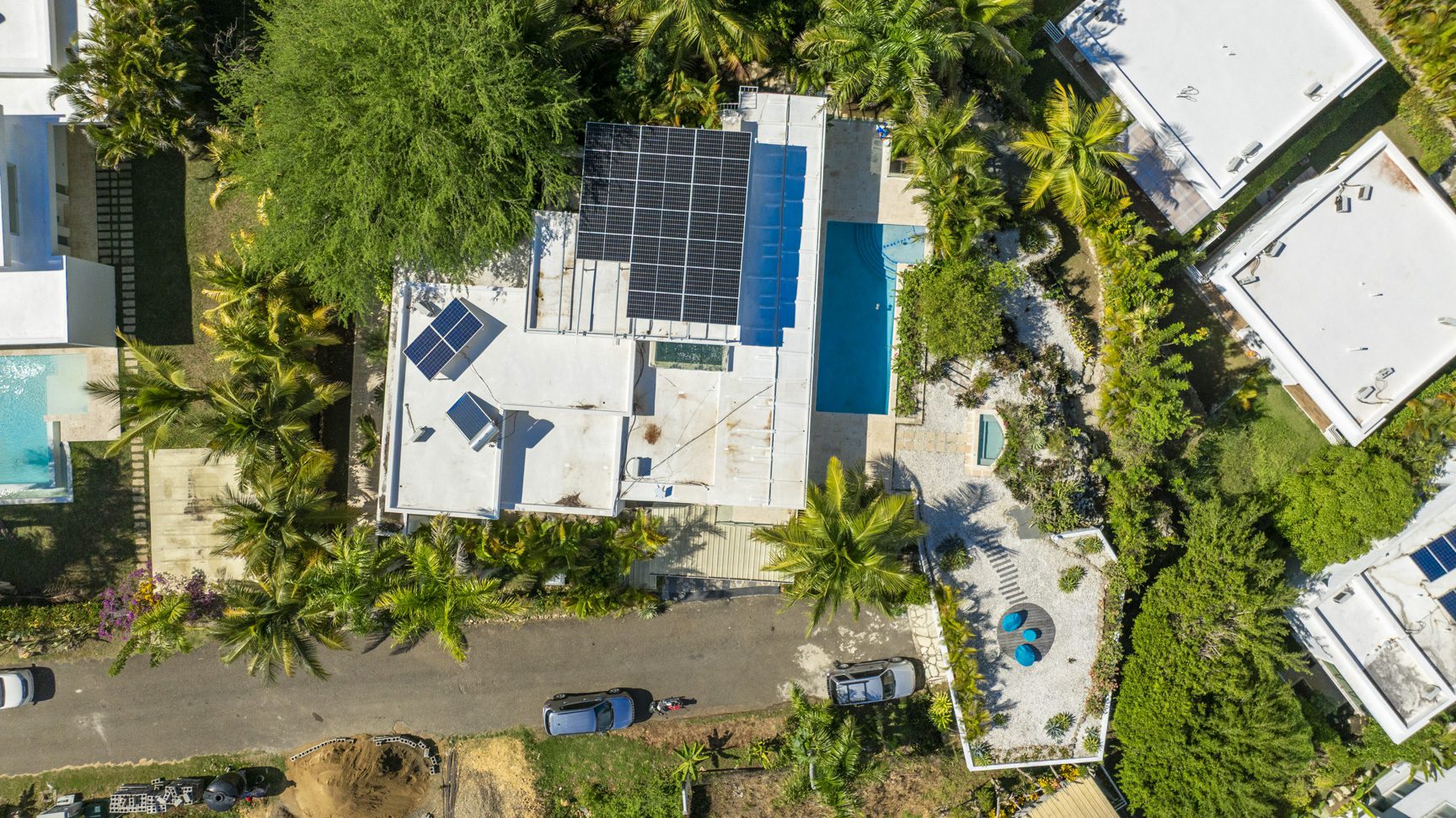 buyDRproperty Aerial view of modern villas with solar panels and pools amidst lush tropical greenery. Sosua Real Estate