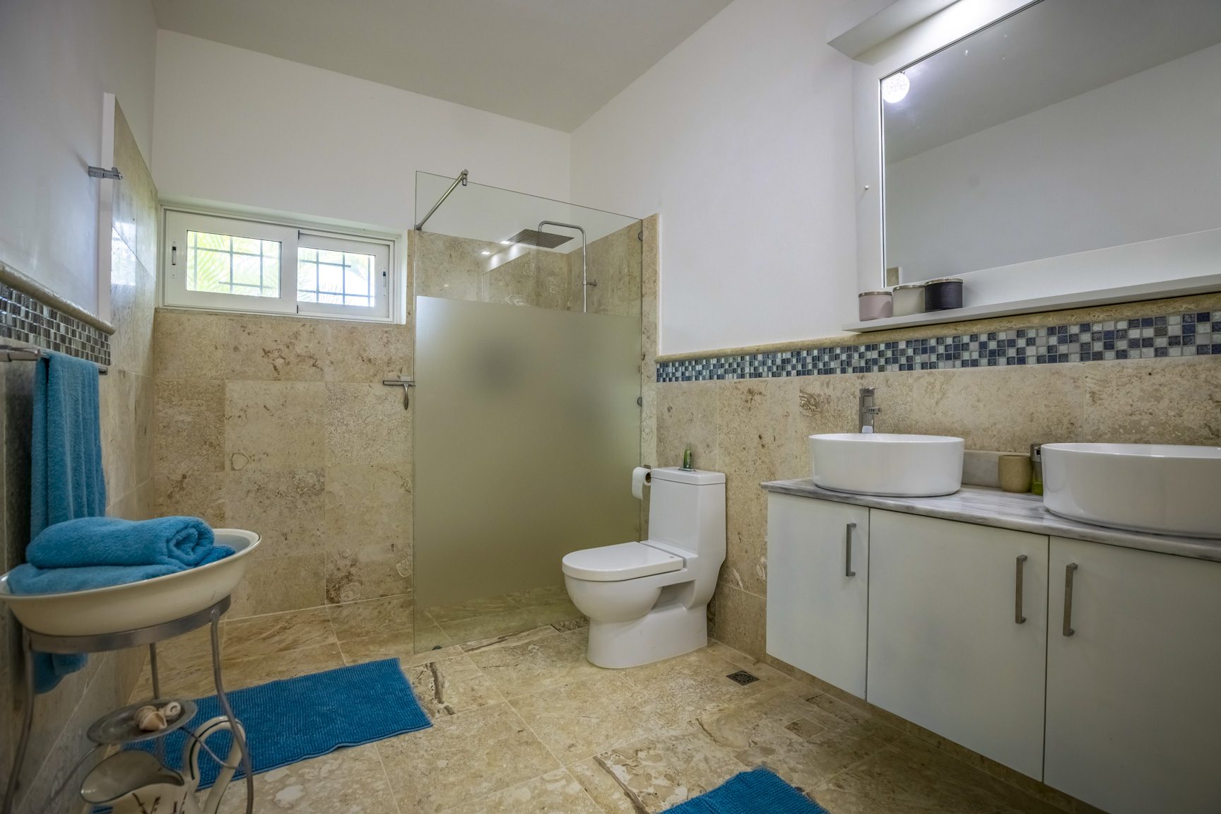 buyDRproperty Modern bathroom with glass shower, double sink, and blue accents Sosua Real Estate