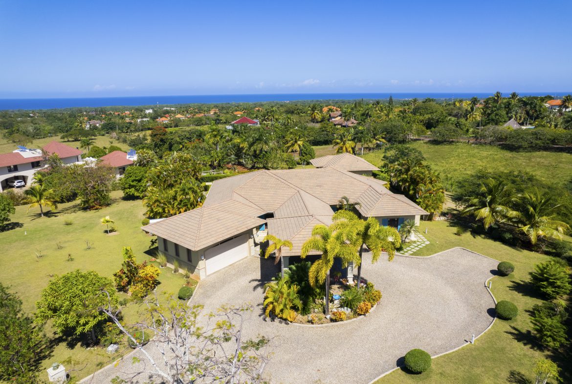 buyDRproperty Spacious villa with manicured lawn and ocean view under clear blue sky Sosua Real Estate
